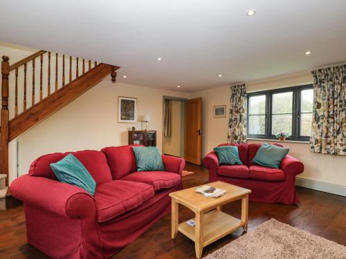 a living room with two red couches and a table at Nine Acres Barn in Marlborough