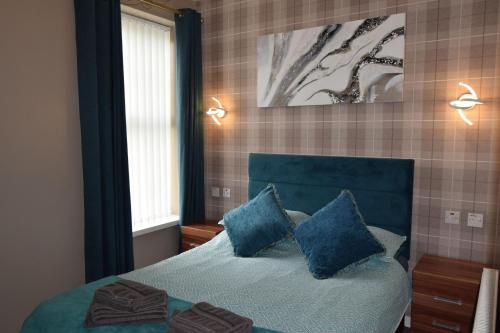 een slaapkamer met een blauw bed met 2 blauwe kussens bij Baxter Holiday Apartments in Blackpool
