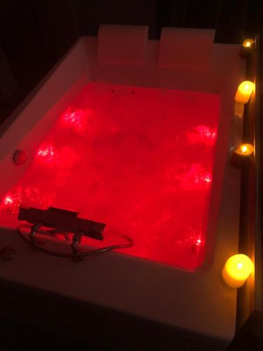 a red bath tub with red lights in it at Chambre privative avec baignoire balneo in Crespin