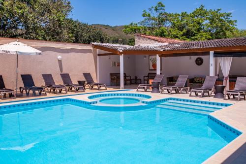 a swimming pool with chaise lounge chairs and a resort at Ciribaí Praia Hotel in Pauba