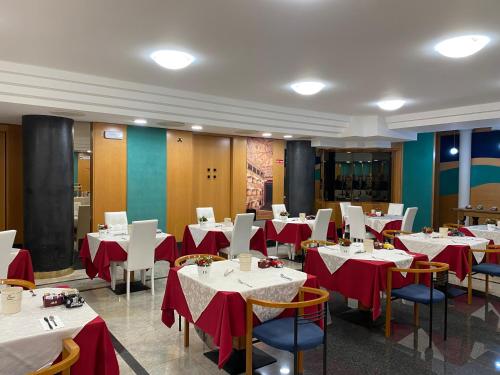 un restaurante con mesas y sillas con manteles rojos y blancos en Hotel Casagrande, en Feltre