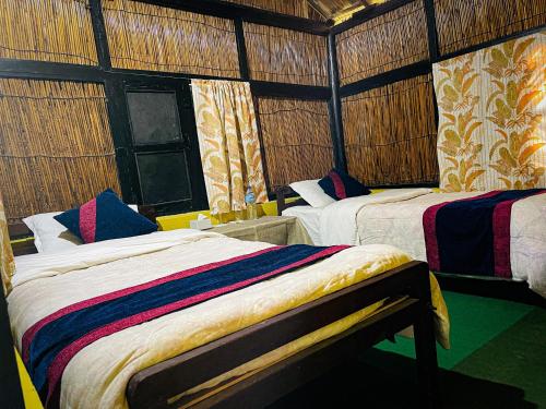 a bedroom with two beds in a room at Hotel Tharu Garden, Sauraha in Sauraha