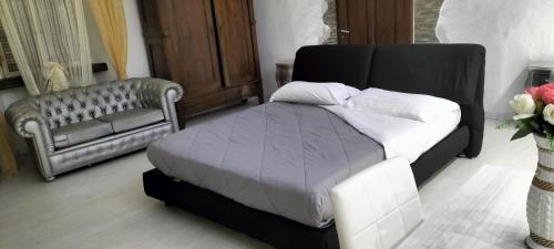1 dormitorio con 1 cama, 1 sofá y 1 silla en white appartament, en Bagnolo Piemonte
