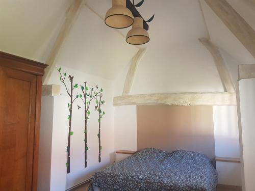 a bedroom with a ceiling fan and trees on the wall at Entre Terre et Mer - La Clé des Champs in Guisy