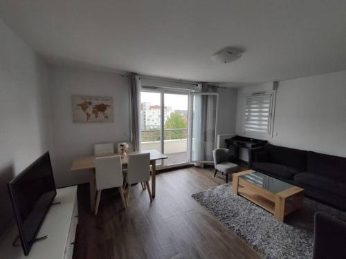 a living room with a table and a couch at App 5 pers, parking, 3mn RER A, 40 mn du centre de Paris, Cergy le Haut in Cergy