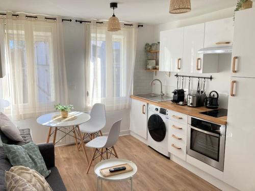 een keuken en een woonkamer met een tafel en stoelen bij L'Appartement Vert in Douai