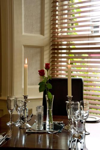 a table with candles and glasses and a rose in a vase at Mills Inn in Ballyvourney