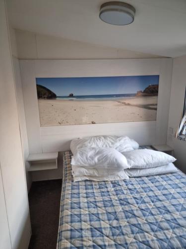 Lyons robin hood lodge Rhyl في ريل: غرفة نوم بسرير مع صورة لشاطئ
