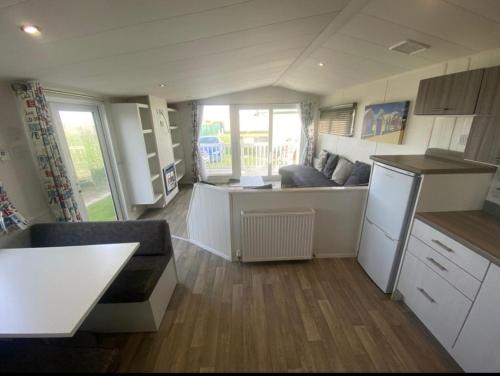 eine Küche und ein Wohnzimmer mit einem Sofa und einem Tisch in der Unterkunft Lyons robin hood lodge Rhyl in Rhyl