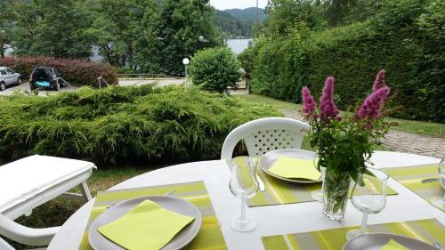 a white table with a vase of purple flowers on it at Les Prairies du lac in Gérardmer