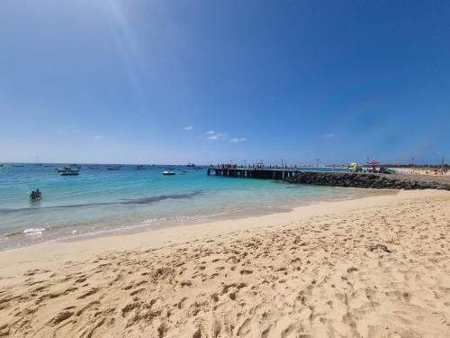 a beach with people in the water and a pier at Daisal Apartment - 2 bedroom apartment with balcony near the beach & city center, perfect for nomads, travellers, families, watersports! in Santa Maria