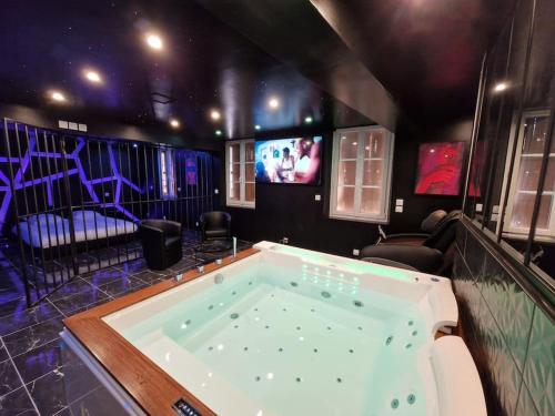 a large tub in a room with a tv at Suite Coquine avec jacuzzi YaoSpa60 