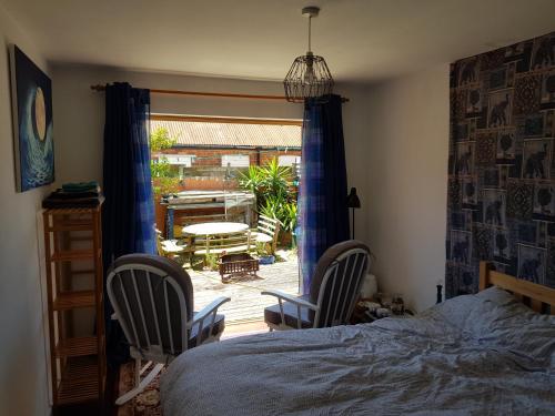 a bedroom with a bed and two chairs and a patio at Garden room in Exmouth
