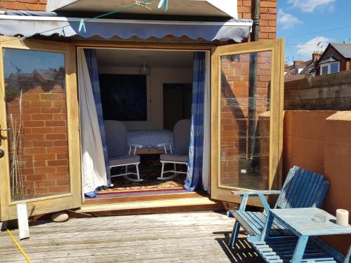 un porche cubierto con 2 sillas y una mesa en Garden room, en Exmouth