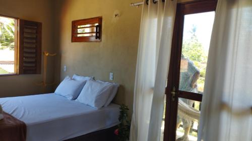 a bedroom with a bed with white pillows and a window at Vila Samin Moitas in Praia de Moitas