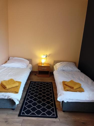 a room with two beds and a table with a lamp at Pokoje Mira in Torzym