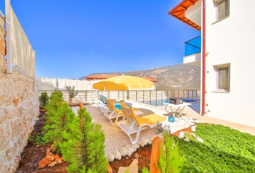 a patio with chairs and umbrellas on the side of a building at James Pansiyon Blue sea view villas Kaş Peninsula in Kas
