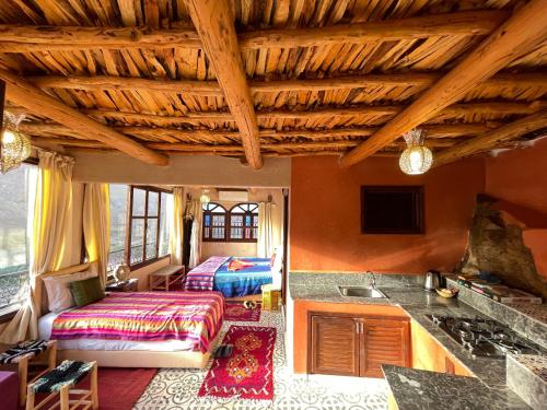 a living room with wooden ceilings and a kitchen at Riad Atlas 4 seasons in Imlil