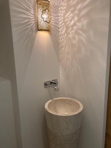 a bathroom with a light on a white wall at CHAMBRES DES EAUX 28 "baptistine" in Sarcey