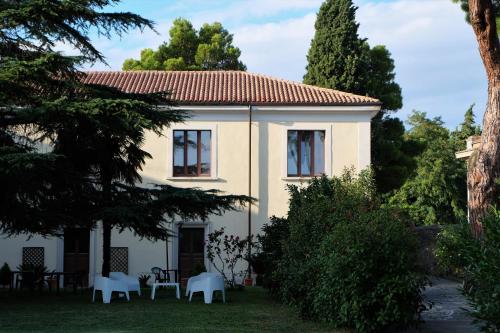 a white house with tables and chairs in the yard at Hostel il Tetto in Melfi