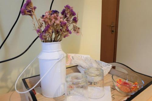 a white vase with purple flowers on a table at Hostel il Tetto in Melfi