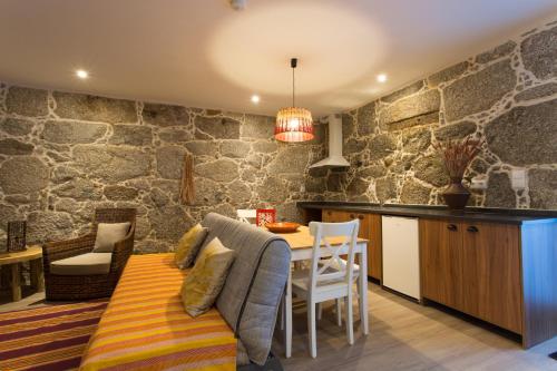 cocina y comedor con pared de piedra en Casa de Campo Sossego da Lata, en Fafe