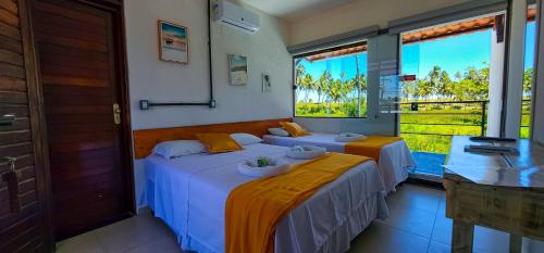two beds in a room with two windows at Pousada Brisa e Mar in Praia do Frances