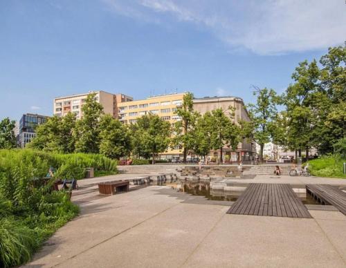 park z ławkami, stawem i budynkami w obiekcie :: Apartment City Center :: w Warszawie