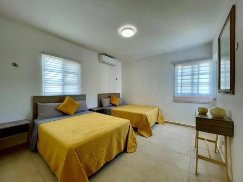a bedroom with two beds with yellow sheets and windows at Casa Mar y Amor in Cancún