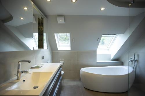 uma casa de banho com uma banheira branca e um lavatório. em Hôtel Restaurant Les Alisiers em Lapoutroie