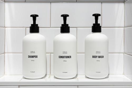 a group of four shampoo bottles on a shelf in a bathroom at Kasa Edison House South End Dilworth Charlotte in Charlotte