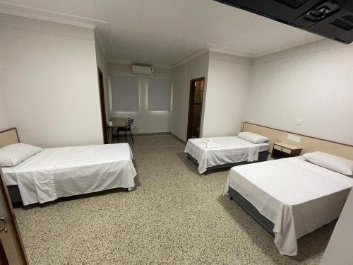 een kamer met 2 bedden en een kamer met 2 tafels bij Bravo City Hotel Sao Carlos in São Carlos
