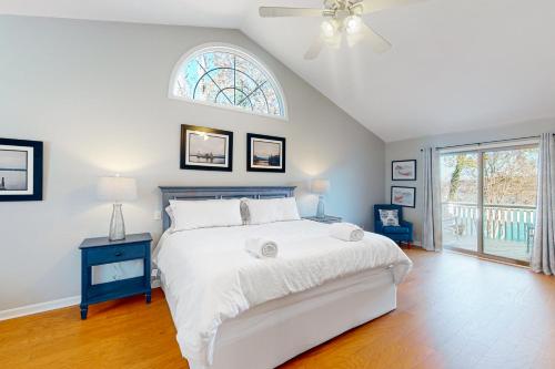 a white bedroom with a bed and a window at The Lake House on Sunset Point in Moneta