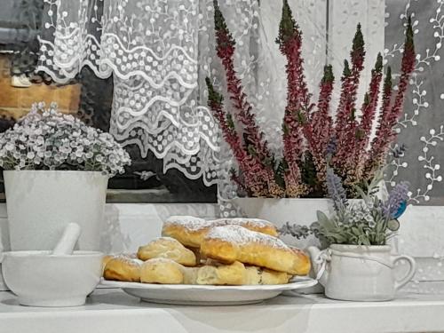 a plate of pastries on a table with cups and flowers at Pod skálou, Mánesova 646 in Úpice