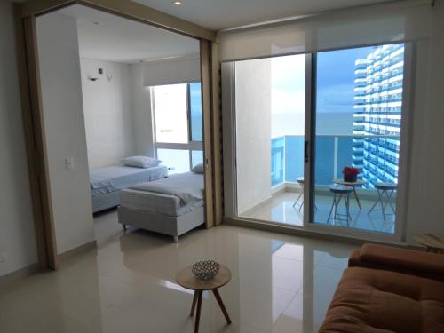 sala de estar con sofá, cama y balcón en Apartamento Reserva Del Mar, en Santa Marta