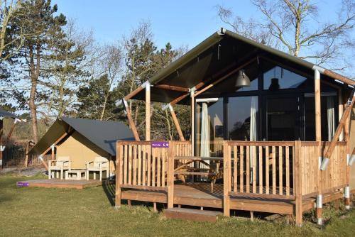 a cabin with a deck with a large window at Safari Lodge, glamping aan zee! in Callantsoog