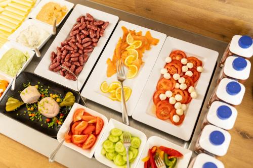 a table filled with different types of food on plates at Das Reinisch Hotel - near Vienna Airport in Schwechat