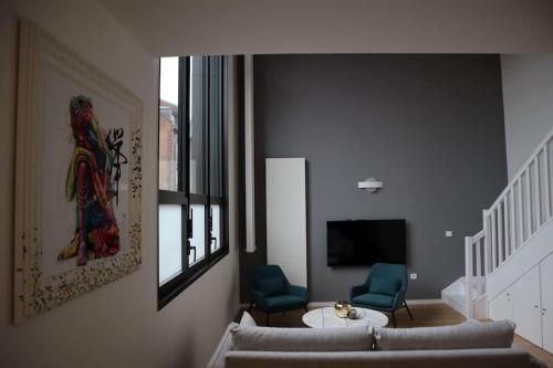 a living room with a couch and two chairs and a television at Superbe duplex en hypercentre ville in Amiens