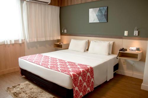 ein Schlafzimmer mit einem großen weißen Bett mit einer roten Decke in der Unterkunft Comfort Hotel Campos dos Goytacazes in Campos dos Goytacazes