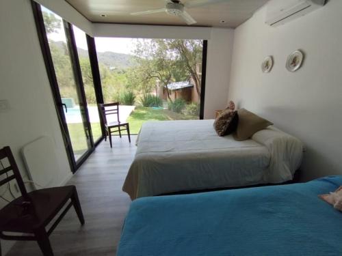 1 Schlafzimmer mit 2 Betten und einem großen Fenster in der Unterkunft Casa en Potrerillo de Larreta in Alta Gracia