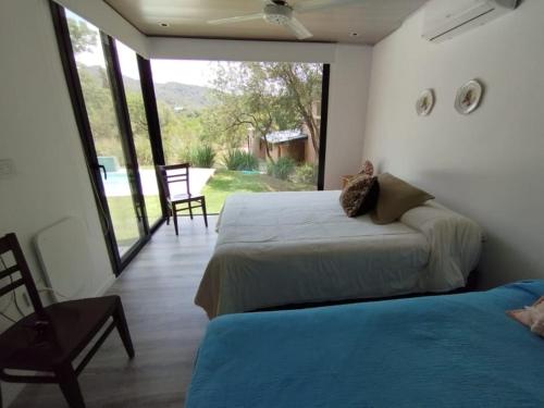 a bedroom with two beds and a large window at Casa en Potrerillo de Larreta in Alta Gracia
