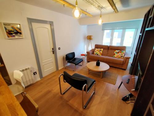 a living room with a couch and a table and chairs at Lotila Flats Playa in Gijón