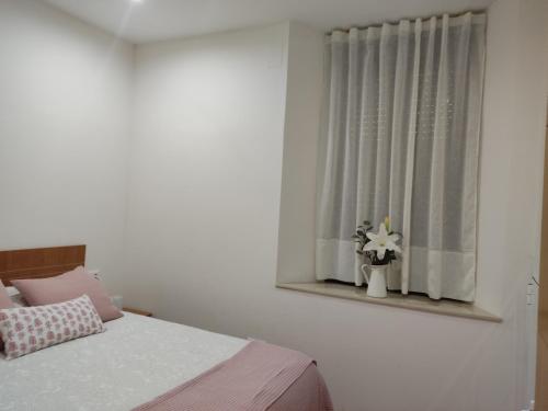 a bedroom with a bed and a window with flowers at Alojamiento turístico Carvi in Arévalo