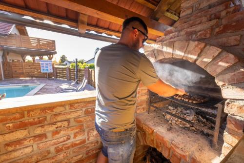 a man putting food into a brick oven at Apartments Galunder in Veržej