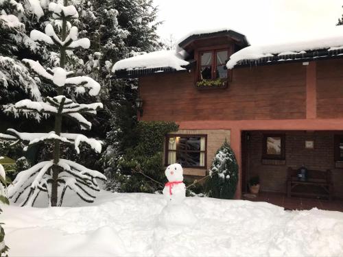 Un ours en peluche debout dans la neige devant une maison dans l'établissement DAT "Lo de Bianca", à San Carlos de Bariloche