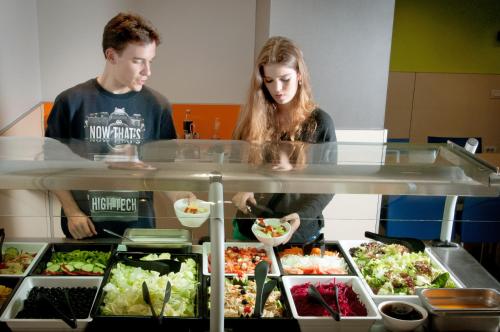 a man and a woman preparing food in a buffet at Alberg Pere Tarrés in Barcelona