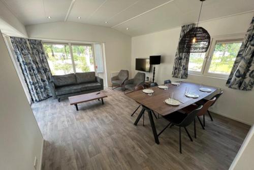 a living room with a table and a living room with a couch at Luxe Chalet Inn Otterlo op de Veluwe aan het Water! in Otterlo