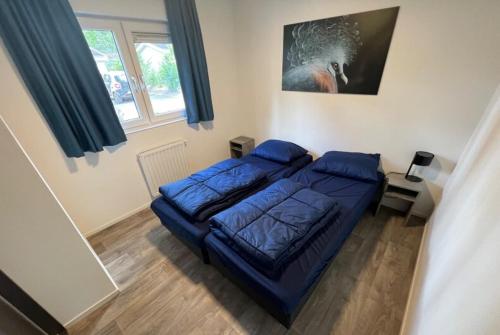 a bedroom with a blue bed and a window at europark chalet exclusif 6 in Otterlo