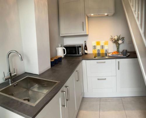 a kitchen with white cabinets and a sink at Pass the Keys Superb space in the idyllic village of Loppington in Shrewsbury
