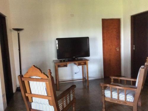 a living room with two chairs and a flat screen tv at Chácara Camargo Silva in Mairiporã